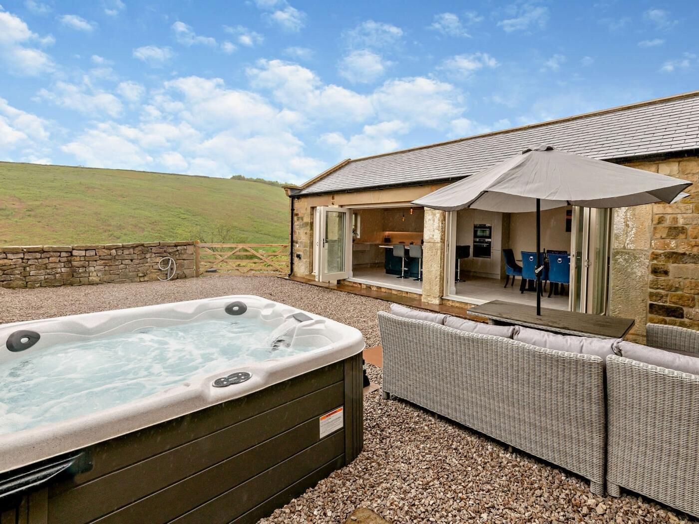 A hot tub, outdoor seating, and a stone building with an open patio.