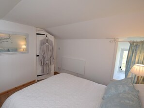 A bedroom with a large bed, a wardrobe, a mirror, and a window with curtains. - 1 Bed in Shetland (oc-75417) (Uyeasound)