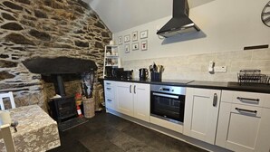 A modern kitchen with a stone wall, a built-in stove, white cabinets, and a black countertop.