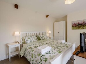 Ein Schlafzimmer mit einem Bett, zwei Nachttischen, einem Kleiderschrank, einem Gemälde und einem Fernseher.