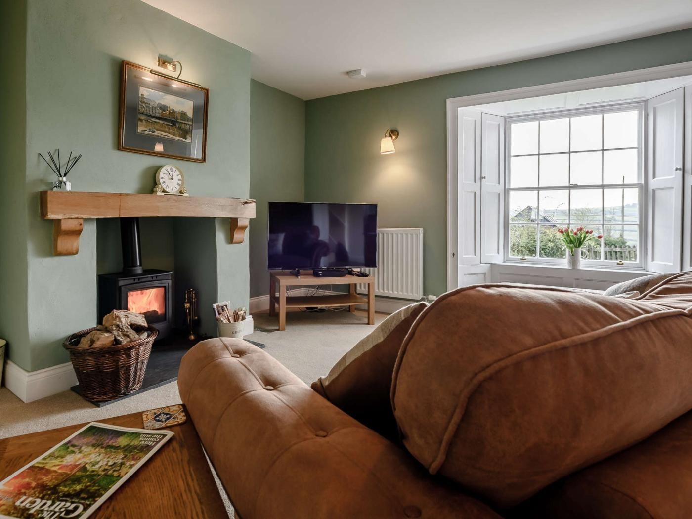 A living room with a fireplace, a television, and a large window.
