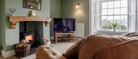 A living room with a fireplace, a television, and a large window.
