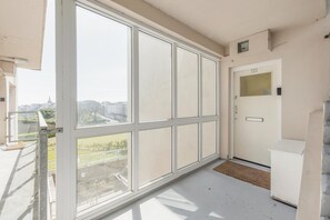 A balcony with large windows, a door with a number plate, and a concrete staircase. - 2 Bed in Tenby (oc-fb065) (Tenby)