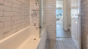 Een moderne badkamer met een douchecabine, een badkuip en een ruime douche.