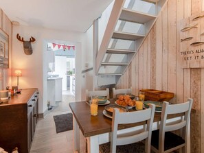 A modern kitchen with a wooden island, white chairs, and a breakfast setup. - 2 Bed in Cromer (oc-kt154) (Cromer)