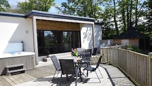 Eine moderne Terrassenausstattung mit Esstisch und Stühlen, einem Whirlpool und einem Holzzaun.