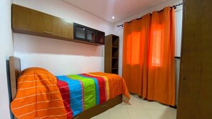 A room with a bed, a wardrobe, a shelf unit, and orange curtains. - Serene 2-bedroom apartment in Cabo Negro with view of golf course (Cabo Negro)