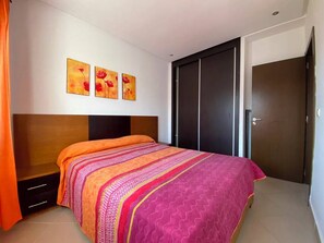 A bedroom with a bed, a wardrobe, and three wall-mounted paintings. - Serene 2-bedroom apartment in Cabo Negro with view of golf course (Cabo Negro)
