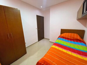 A bedroom with a bed, a wardrobe, and a door.