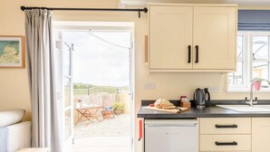 Et lille køkken med et køleskab, en vask og et spiseområde med et bord og stole.