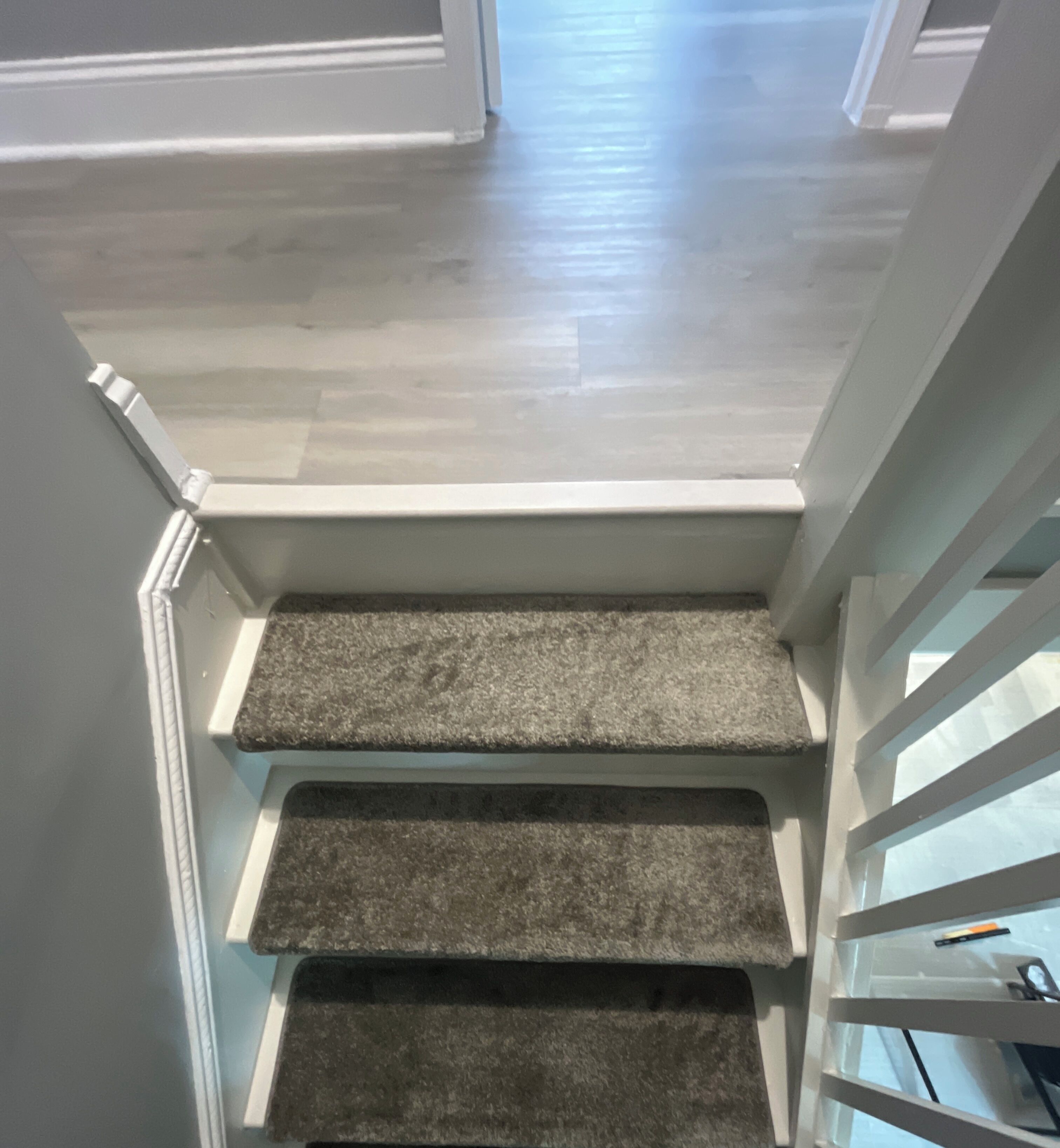Una escalera con peldaños alfombrados y barandillas blancas.