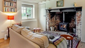 A cozy living room with a fireplace, a sofa, a bookshelf, and a window. - 1 Bed in Wootton (oc-ic159) (Wootton Bridge)