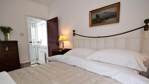 Une chambre à coucher avec un lit, une table de chevet, une lampe, une commode et une porte.