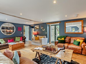 A living room with a fireplace, a coffee table, and a bookshelf. - 5 Bed in Dulverton (oc-41133) (Brushford)