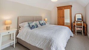 Une chambre à coucher comprenant un lit, des tables de chevet, une commode, un miroir et un luminaire au plafond.