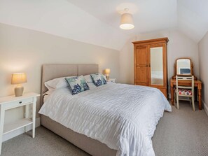 Ein Schlafzimmer mit einem Bett, Nachttischen, einem Schminktisch und einer Deckenleuchte.