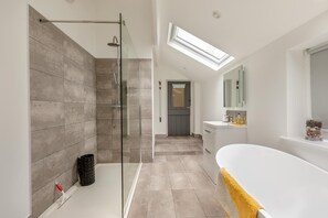 Une salle de bain moderne dotée d’une douche à parois de verre, d’un meuble-lavabo ouvert et d’une fenêtre de toit.