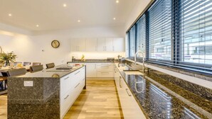 Eine moderne Küche mit Granit Arbeitsplatte, weißen Schränken und einem großen Fenster mit Jalousien.