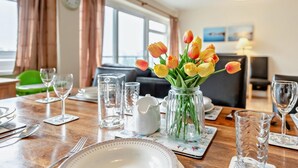 Een eettafel gedekt met borden, bestek, glazen en een vaas tulpen.