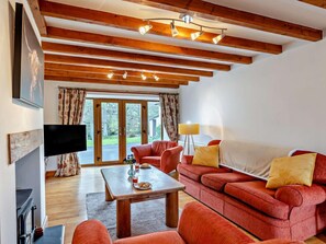 A modern living room with a wooden ceiling, a sofa set, a coffee table, and a television.