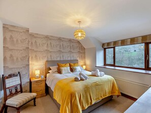 A bedroom with a large bed, a nightstand, a chair, a window with a view, and a decorative wall.