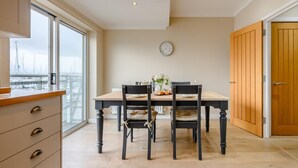 Un coin repas comprenant une table, des chaises, une horloge et une vue par la fenêtre.