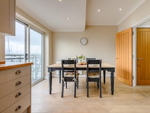 A dining area with a table, chairs, a clock, and a view through a window. - 3 Bed in Plymouth (oc-45208) (Plymouth)