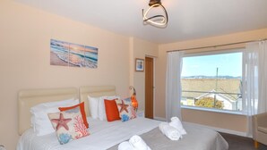 Une chambre d’hôtel avec un lit, une fenêtre donnant sur un beau paysage et un tableau accroché au mur.