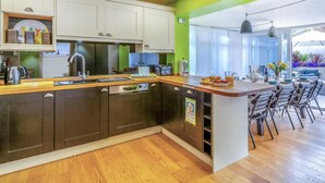 Une cuisine moderne dotée d’un plan de travail en bois, d’appareils électroménagers en acier inoxydable et d’un coin repas offrant une vue agréable.