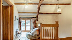 A room with wooden beams, a bed, a bench, a rug, and a window with curtains. - 2 Bed in Exeter (oc-92739) (Longdown)
