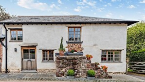 A two-story house with a stone foundation, a wooden door, and multiple windows. - 2 Bed in Exeter (oc-92739) (Longdown)