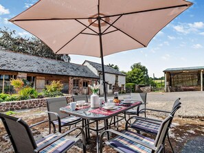 An outdoor dining area with a table set for four, surrounded by chairs with patterned cushions, under a large umbrella. - 2 Bed in Exeter (oc-92739) (Longdown)