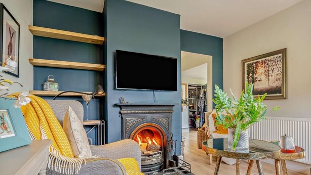 Ein Wohnzimmer mit Kamin, einer Couch, einem Fernseher und einem Bücherregal.