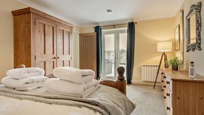 A hotel room with a bed, a wooden dresser, a lamp, and a view through a glass door. - 1 Bed in Fordingbridge (oc-88364) (Godshill)