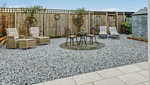 A patio with wicker furniture, a round table, and a wooden fence. - 1 Bed in Fordingbridge (oc-88364) (Godshill)