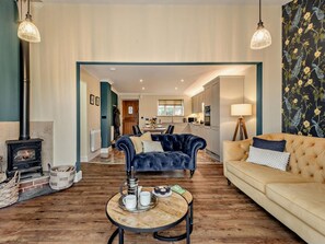 A living room with a fireplace, a sofa, a coffee table, and a view into the kitchen. - 1 Bed in Fordingbridge (oc-88364) (Godshill)