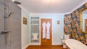 A bathroom with a shower, a bathtub, a toilet, and a door leading to a room with two white robes hanging. - 1 Bed in Fordingbridge (oc-88364) (Godshill)