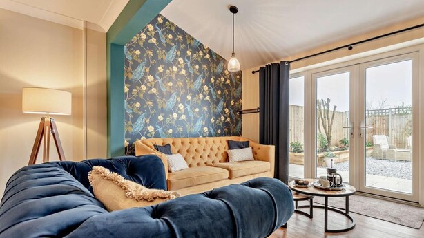 A living room with a sofa, a lamp, a patterned wall, and a view through a glass door. - 1 Bed in Fordingbridge (oc-88364) (Godshill)