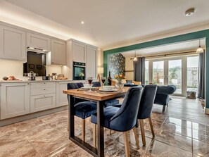 A modern kitchen with a dining area, featuring a marble floor, a dining table with chairs, and a view of the outside. - 1 Bed in Fordingbridge (oc-88364) (Godshill)