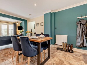A dining area with a table set for two, a sofa, and a coat rack with jackets. - 1 Bed in Fordingbridge (oc-88364) (Godshill)