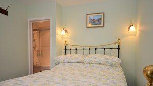 A bed with a floral bedspread, a black metal headboard, and two wall-mounted light fixtures. - 1 Bed in Sturminster Newton (oc-29117) (Hazelbury Bryan)
