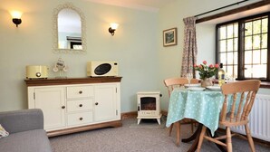 A cozy room with a dining table, chairs, a sofa, a cabinet, a mirror, wall sconces, and a window with curtains. - 1 Bed in Sturminster Newton (oc-29117) (Hazelbury Bryan)