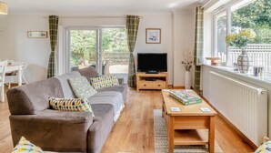 A living room with a sofa, television, and a table with a board game. - 1 Bed in Fordingbridge (oc-49266) (Frogham)