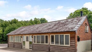 A small, single-story brick building with a sloped roof, large windows, and a door. - 2 Bed in Blandford Forum (oc-83013) (Woolland)