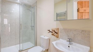 A bathroom with a glass-enclosed shower, a toilet, and a sink with a mirror above. - 2 Bed in Blandford Forum (oc-83013) (Woolland)