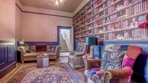 A library with bookshelves, a staircase, and a seating area with a rug. - 4 Bed in Lyndhurst (oc-nfl57) (Lyndhurst)