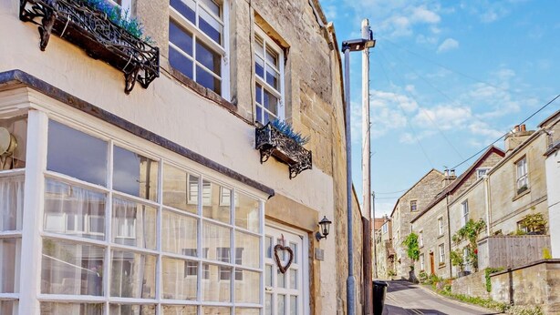 Une rue étroite bordée de bâtiments traditionnels, une porte blanche et un ciel dégagé.