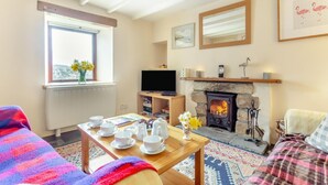 A cozy living room with a fireplace, a television, and a dining area with a table set for tea.