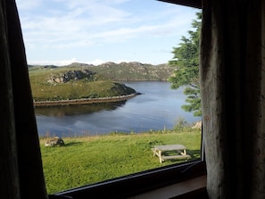 Udsigt over en sø med en græsplæne og en træbænk.