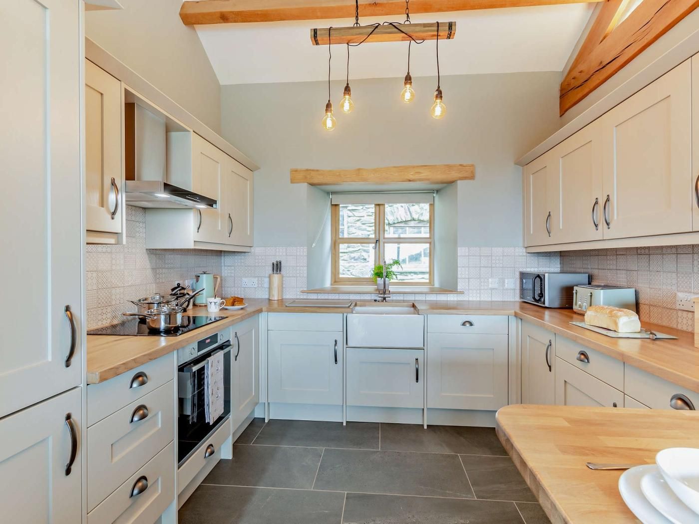 A modern kitchen with light-colored cabinets, a central island, and a built-in oven.